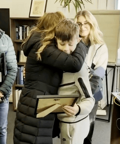 12-летний мальчик обнимает мать во время церемонии благодарности после спасения ее жизни за рулем