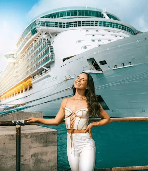 Молода жінка робить селфі біля борту великого круїзного судна під сонячним небом
