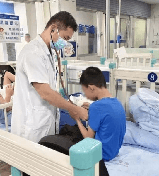 Медик в маске с проверяет состояние мальчика в палате больницы в Китае