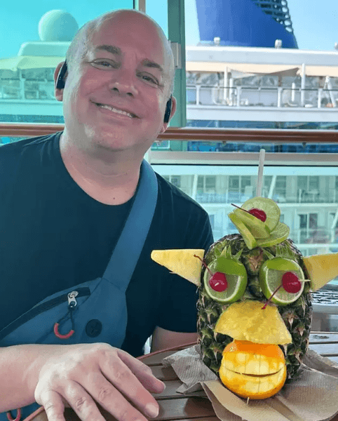Чоловік на борту круїзного лайнера позує з декоративним коктейлем в ананасі