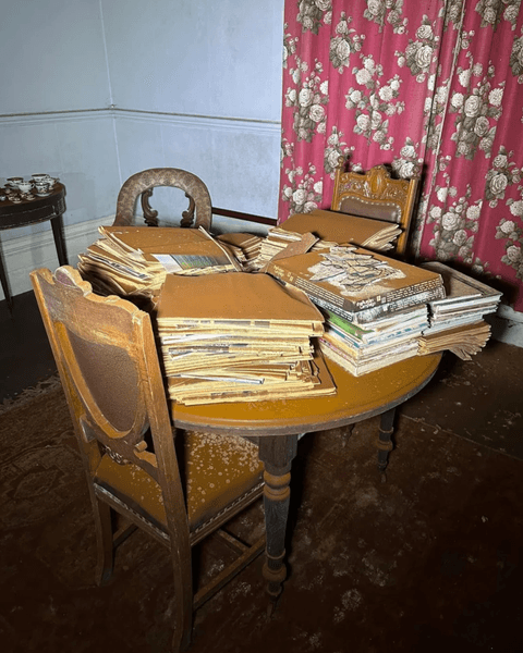 Запилений стіл зі стосами старих журналів і паперів у будинку, де час зупинився