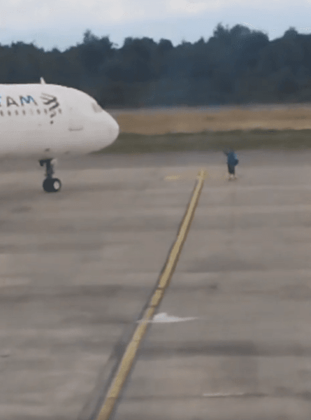 Пассажир выбежал перед самолетом, взлетная полоса, мужчина хотел остановить самолет, опоздал на самолет, пропустил рейс