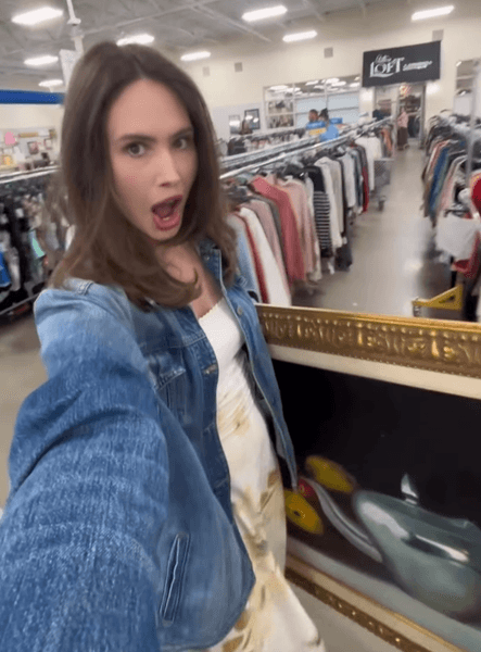 Американка купує велику картину в золотій рамі в магазині вживаних речей