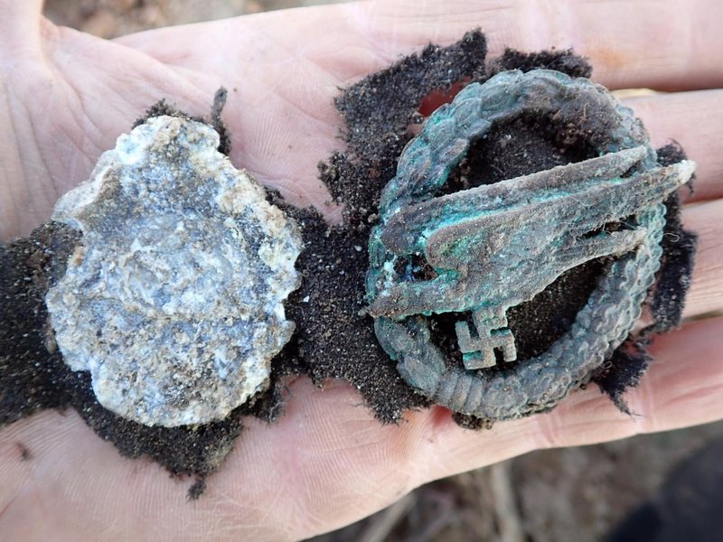 Артефакт Среди других найденных предметов были повреждены знаки различия и обломки снаряжения