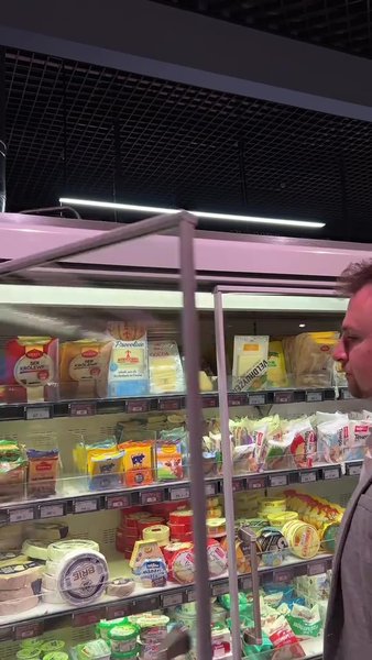 Чоловік купує сир у супермаркеті