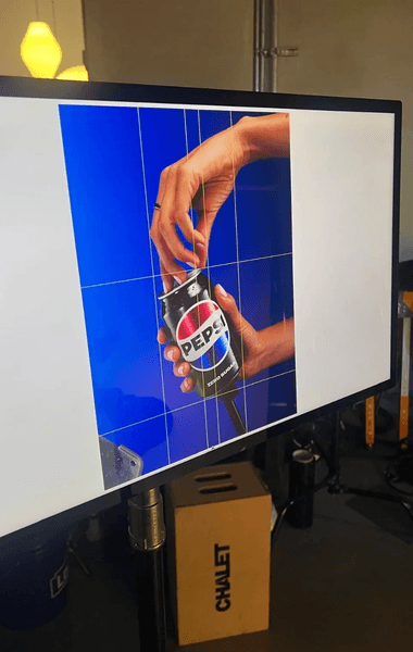 Близък план на ръка, отваряща кутия Pepsi на компютърен екран по време на професионална фотосесия.