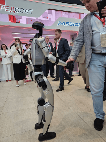 Робот Володя жмет руку посетителю экономического форума