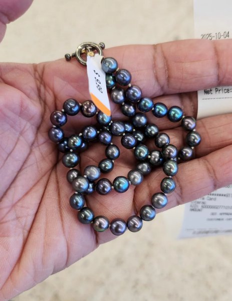 Ожерелье из черного пресноводного жемчуга с ценником $9.99 лежит в руке покупательницы