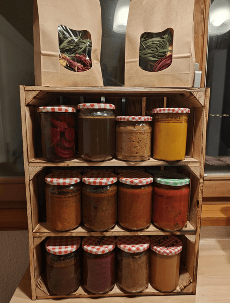 Коробка с аккуратно расставленными домашними консервами и макаронами, практичный рождественский подарок для пожилого человека